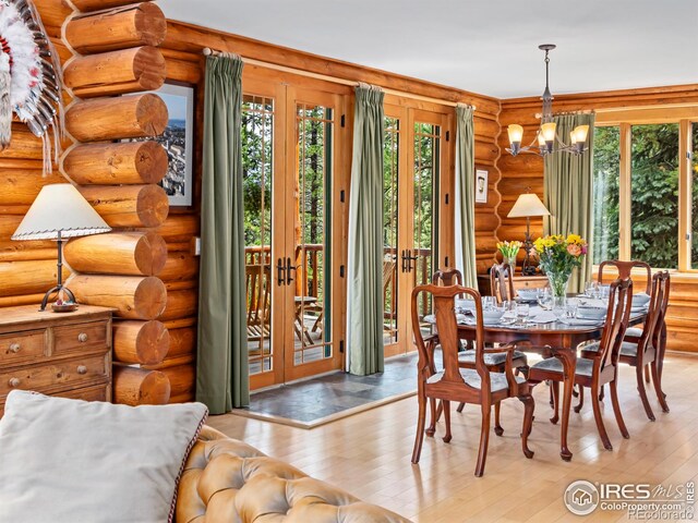 dining area featuring french doors, rustic walls, a chandelier, and hardwood / wood-style flooring