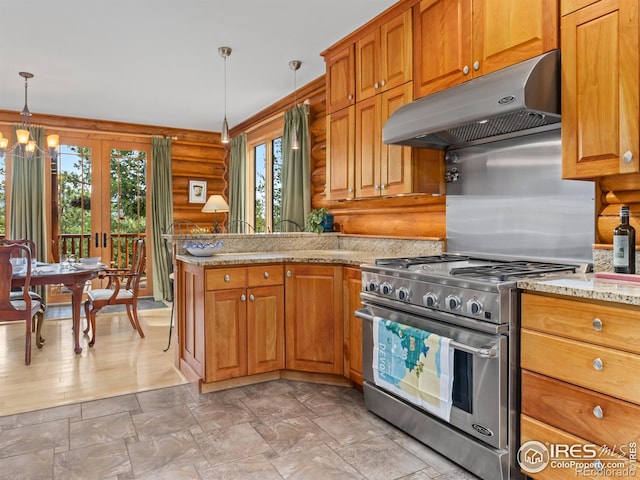 kitchen featuring high end stainless steel range oven, under cabinet range hood, rustic walls, a peninsula, and hanging light fixtures