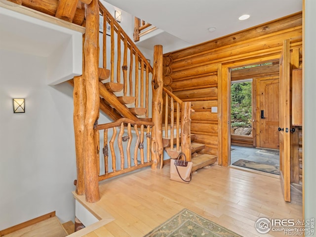 staircase with rustic walls, wood finished floors, baseboards, and recessed lighting