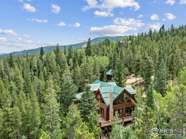 view of subject property with a heavily wooded area and a mountainous background