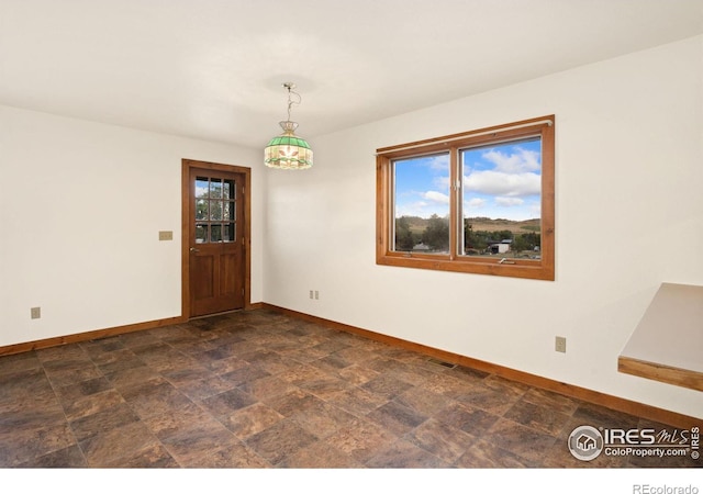 empty room with a healthy amount of sunlight and dark tile patterned flooring