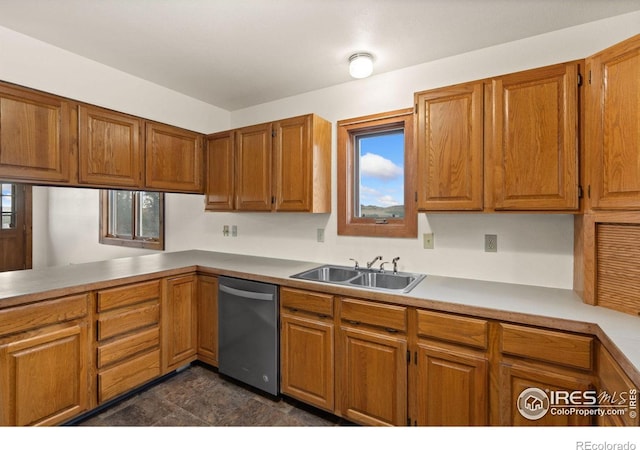 kitchen with dark tile patterned floors, stainless steel dishwasher, and sink