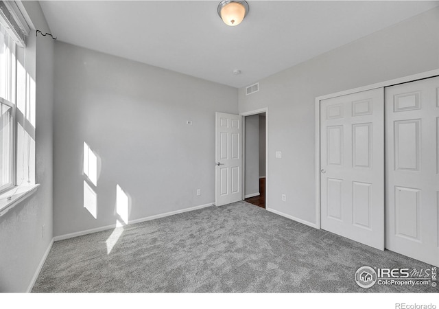 unfurnished bedroom featuring a closet, carpet, visible vents, and baseboards