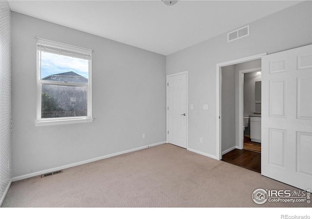 unfurnished bedroom with carpet, visible vents, and baseboards