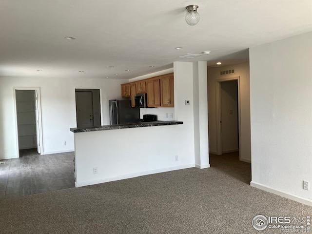 kitchen featuring freestanding refrigerator, brown cabinets, baseboards, dark carpet, and recessed lighting