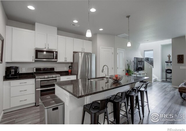 kitchen with appliances with stainless steel finishes, decorative light fixtures, sink, and a center island with sink