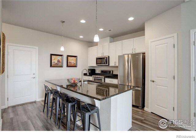 kitchen featuring white cabinets, hanging light fixtures, light hardwood / wood-style flooring, stainless steel appliances, and sink