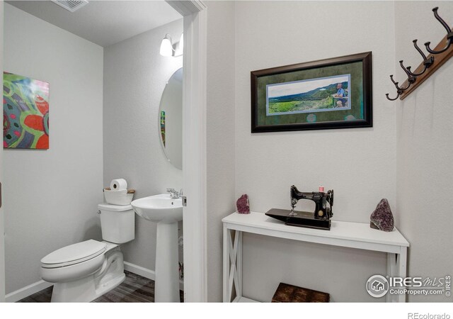 bathroom with toilet, hardwood / wood-style flooring, and sink