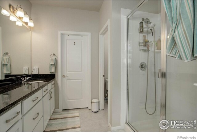 bathroom featuring vanity, toilet, an enclosed shower, and tile patterned floors