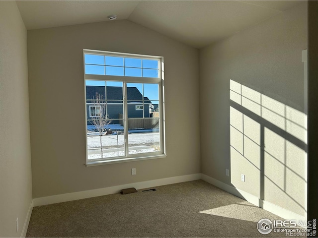 carpeted spare room featuring lofted ceiling and a healthy amount of sunlight