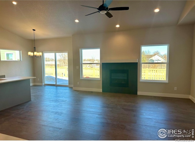 unfurnished living room with ceiling fan with notable chandelier and dark hardwood / wood-style floors