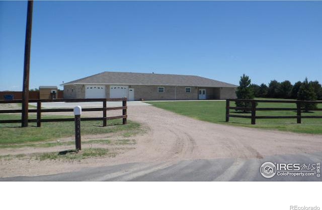 view of front facade with a garage, a rural view, and a front lawn