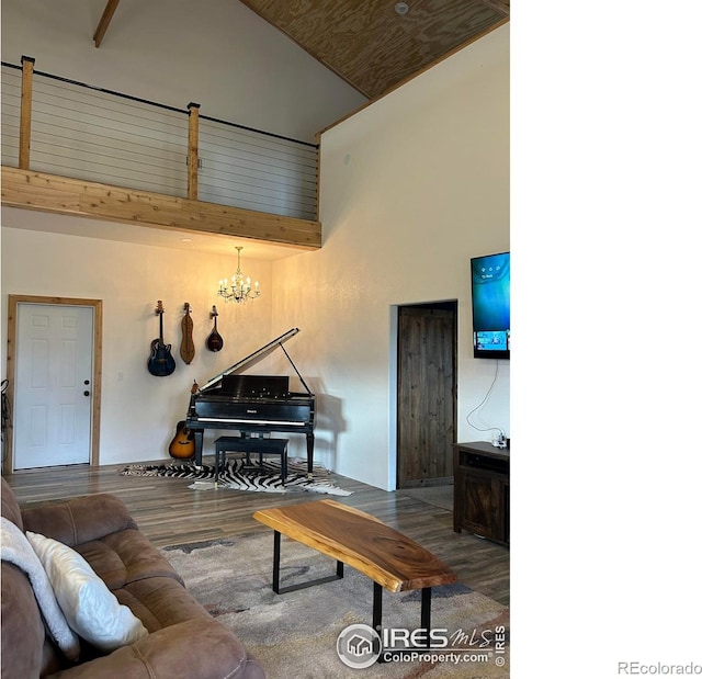 living room with a towering ceiling, a chandelier, and wood finished floors