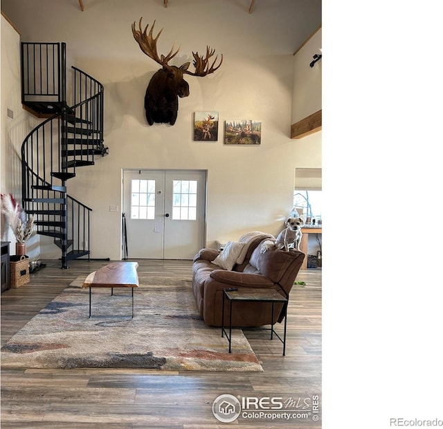 living area featuring a towering ceiling, stairs, wood finished floors, and french doors