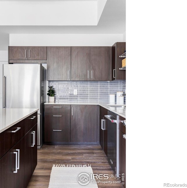 kitchen featuring dark wood-style floors, backsplash, stainless steel appliances, and light countertops