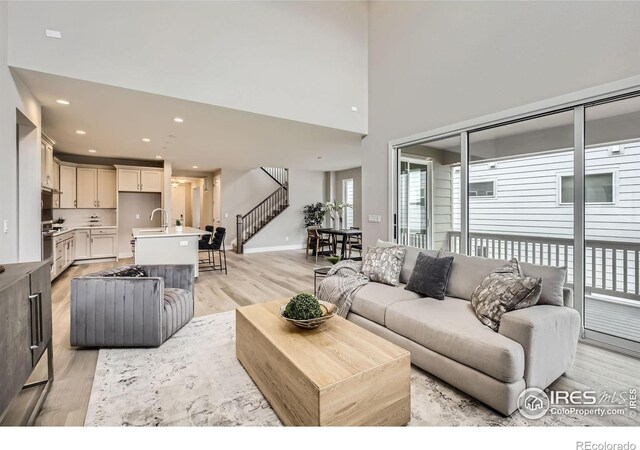 3140 Newfound Lake Rd, Berthoud, CO 80513 - living room featuring stairs, recessed lighting, light wood-type flooring, baseboards, and a towering ceiling