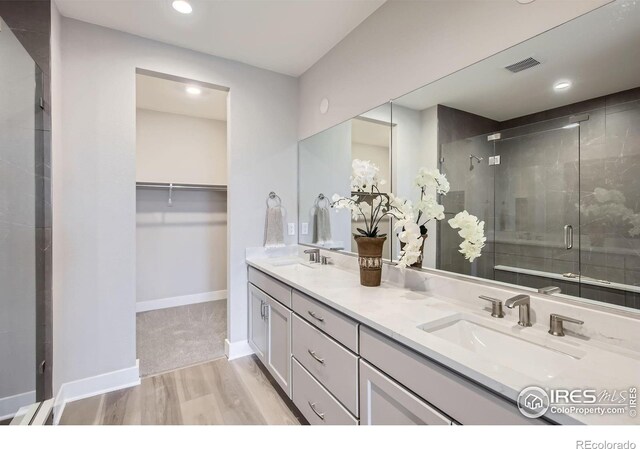 3140 Newfound Lake Rd, Berthoud, CO 80513 - bathroom with double vanity, wood finished floors, a sink, a stall shower, and a spacious closet