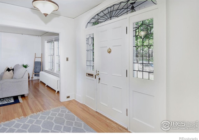 foyer entrance featuring light wood-type flooring and radiator heating unit