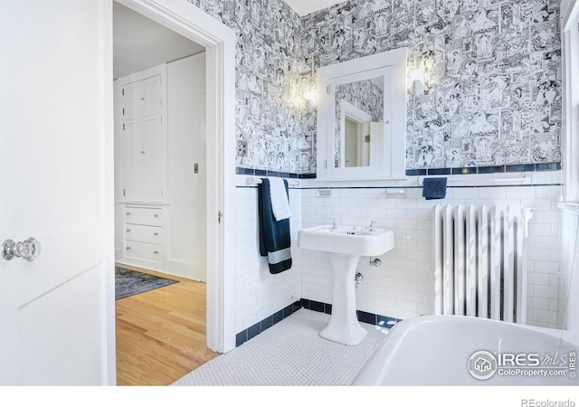 bathroom featuring tile walls, radiator, and hardwood / wood-style floors