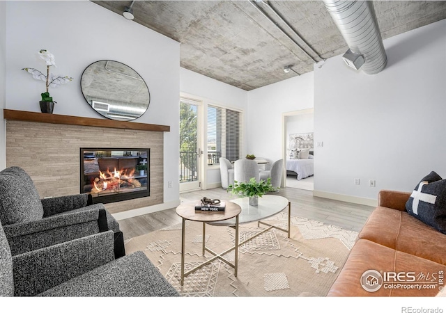 living area featuring baseboards, a tiled fireplace, and wood finished floors