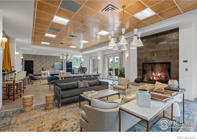 living area featuring a large fireplace, visible vents, and a drop ceiling