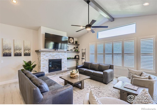 living room featuring a stone fireplace, lofted ceiling with beams, a healthy amount of sunlight, and light wood-type flooring