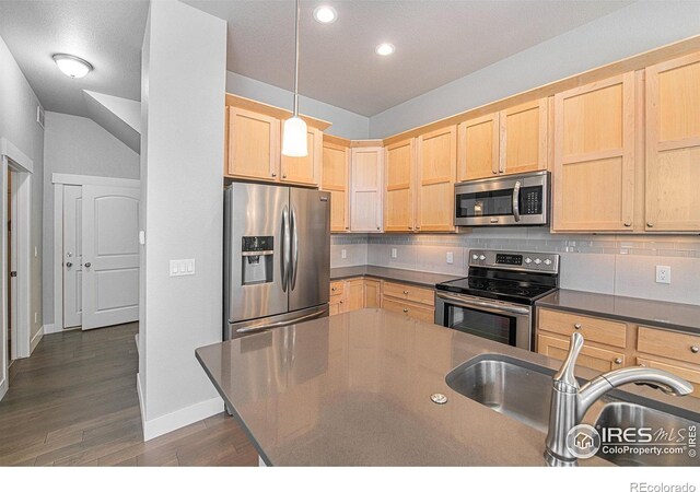 kitchen with pendant lighting, backsplash, vaulted ceiling, dark hardwood / wood-style floors, and appliances with stainless steel finishes