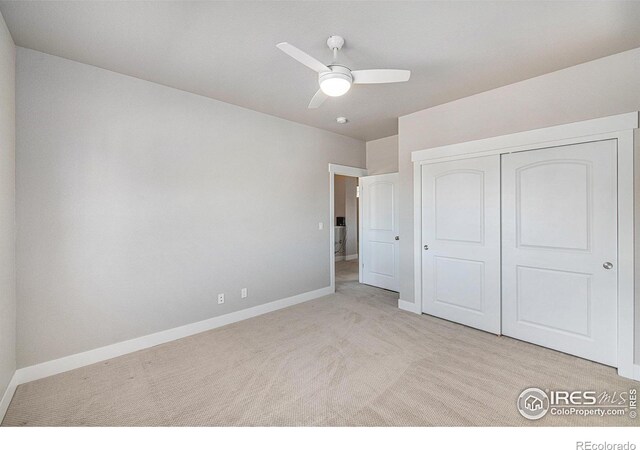 unfurnished bedroom with light carpet, ceiling fan, and a closet