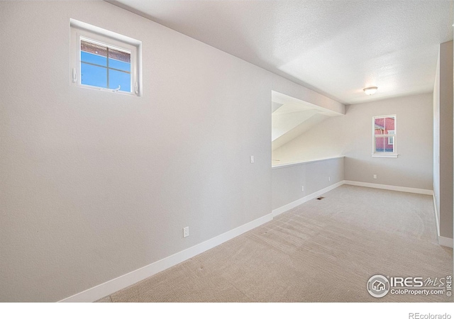 carpeted spare room featuring a textured ceiling and plenty of natural light