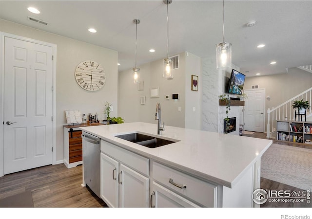 kitchen featuring dishwasher, an island with sink, sink, hardwood / wood-style flooring, and white cabinets