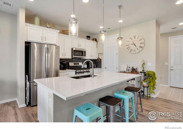 kitchen featuring light hardwood / wood-style floors, appliances with stainless steel finishes, white cabinetry, and tasteful backsplash