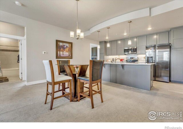 dining space with light colored carpet, a notable chandelier, and sink