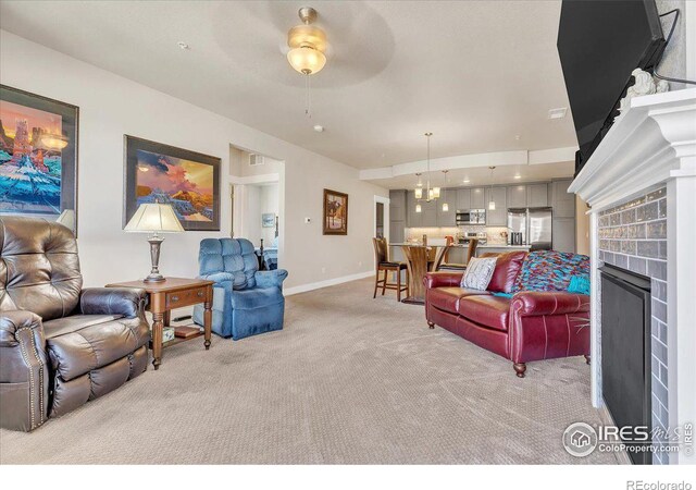 living room with ceiling fan, light carpet, and a brick fireplace