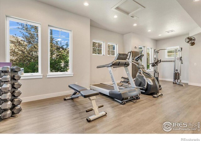 workout area with light wood-type flooring and a textured ceiling