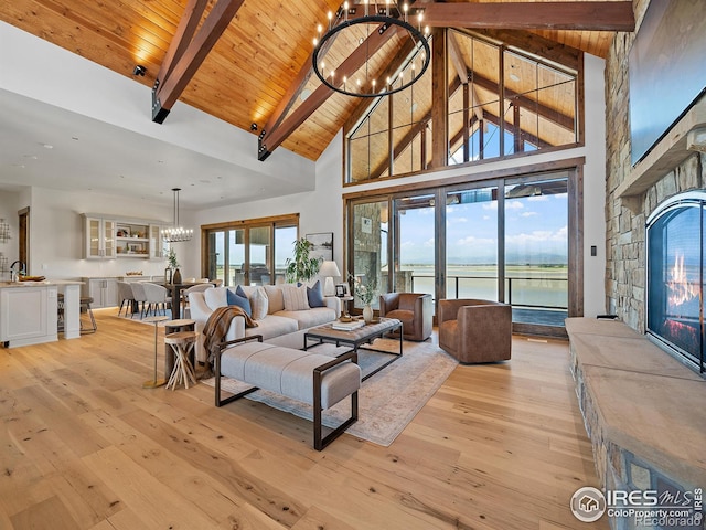 living area featuring light wood finished floors, wood ceiling, a water view, an inviting chandelier, and a fireplace