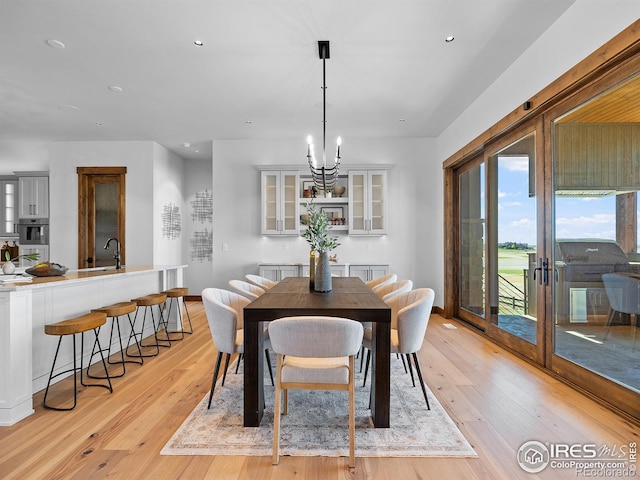 dining area with french doors, recessed lighting, an inviting chandelier, and light wood-style floors