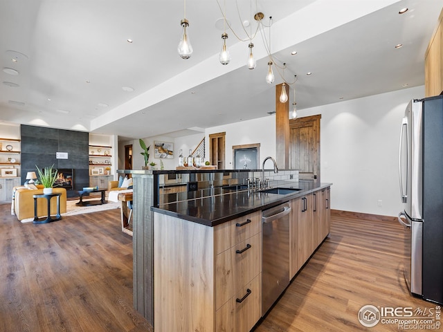 kitchen featuring modern cabinets, appliances with stainless steel finishes, open floor plan, light brown cabinets, and a sink