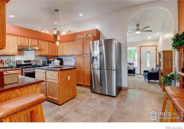 kitchen featuring appliances with stainless steel finishes, a kitchen island, backsplash, and ceiling fan