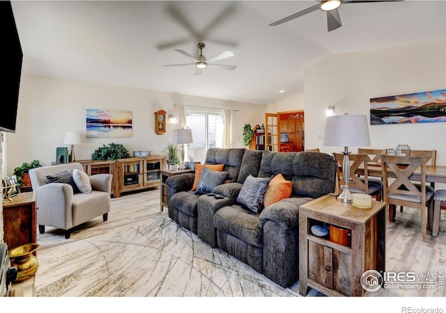 living room featuring vaulted ceiling, light hardwood / wood-style flooring, and ceiling fan