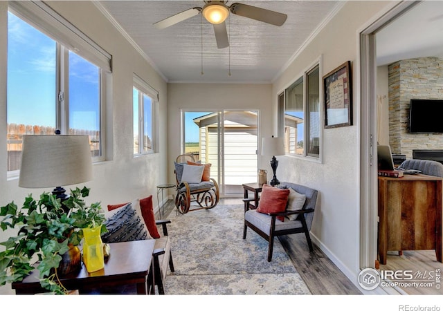 sunroom with ceiling fan and a stone fireplace