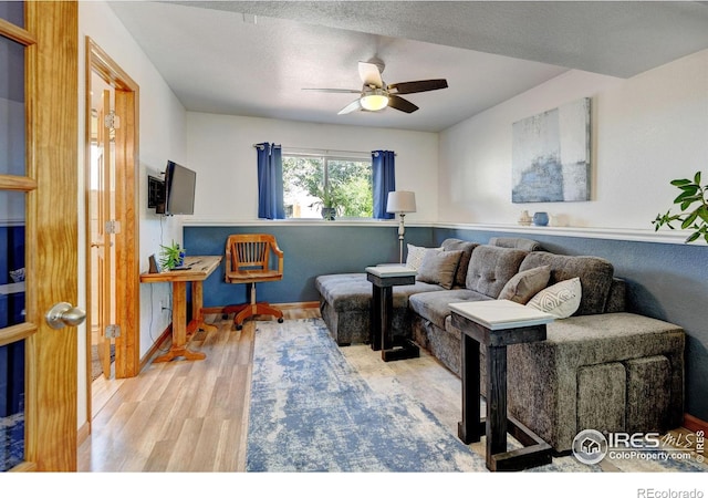 living room featuring hardwood / wood-style floors, ceiling fan, and a textured ceiling