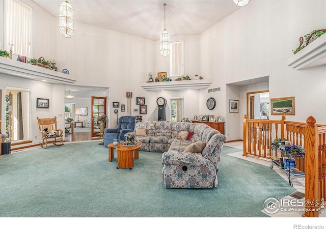 living room with a wealth of natural light, carpet, a towering ceiling, and a chandelier