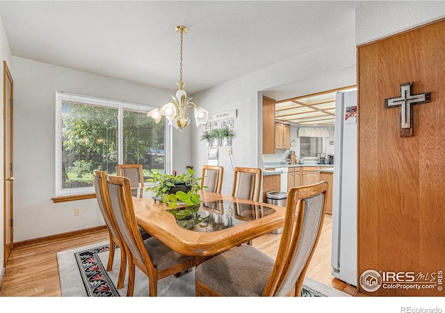 dining area with light hardwood / wood-style flooring and a notable chandelier