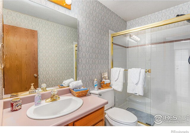 bathroom with a textured ceiling, vanity, toilet, and walk in shower