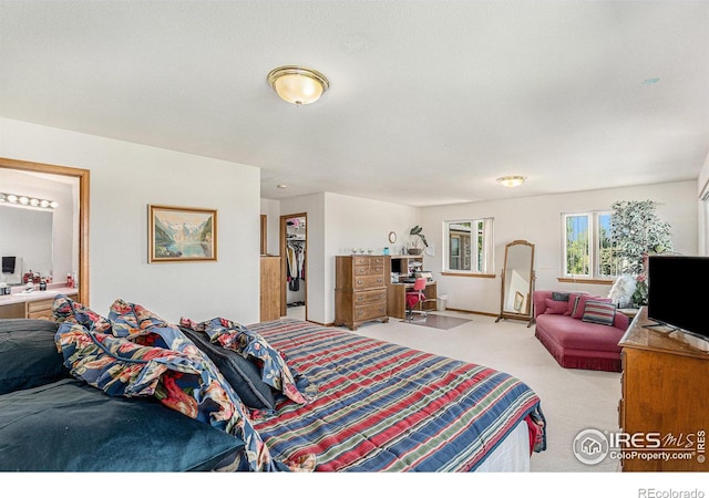 bedroom with a closet, a spacious closet, carpet floors, and ensuite bathroom