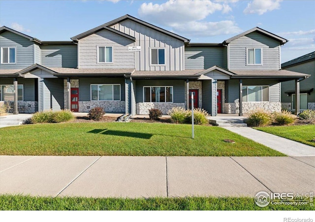 view of front of property featuring stone siding, board and batten siding, and a front yard