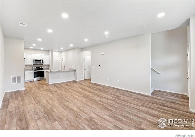 unfurnished living room with light hardwood / wood-style floors and sink