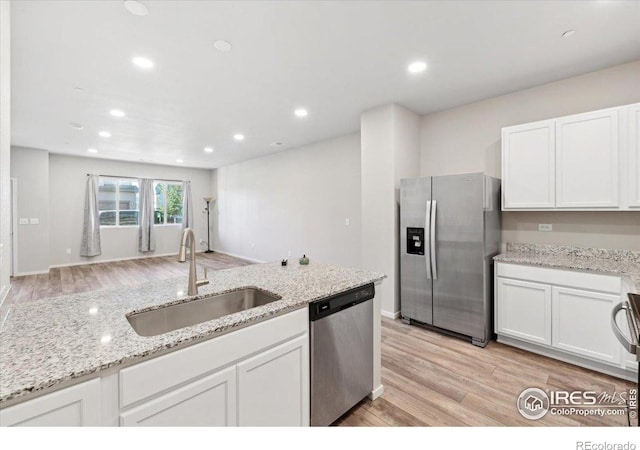 kitchen featuring sink, white cabinets, light hardwood / wood-style flooring, stainless steel appliances, and light stone countertops