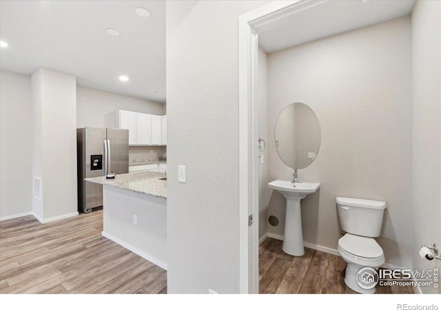 bathroom featuring toilet, recessed lighting, baseboards, and wood finished floors