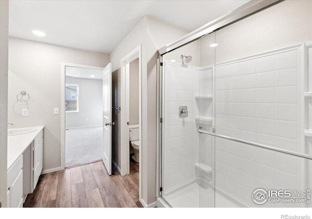 full bathroom with a stall shower, wood finished floors, toilet, and vanity